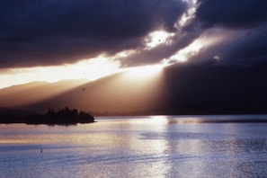 Sunlight breaking through clouds over a calm fjord, reflecting hope and steady growth.