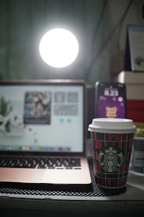 A sleek, modern workspace with a laptop, smartphone, and a cup of coffee, bathed in soft blue light reflecting the brand colors.