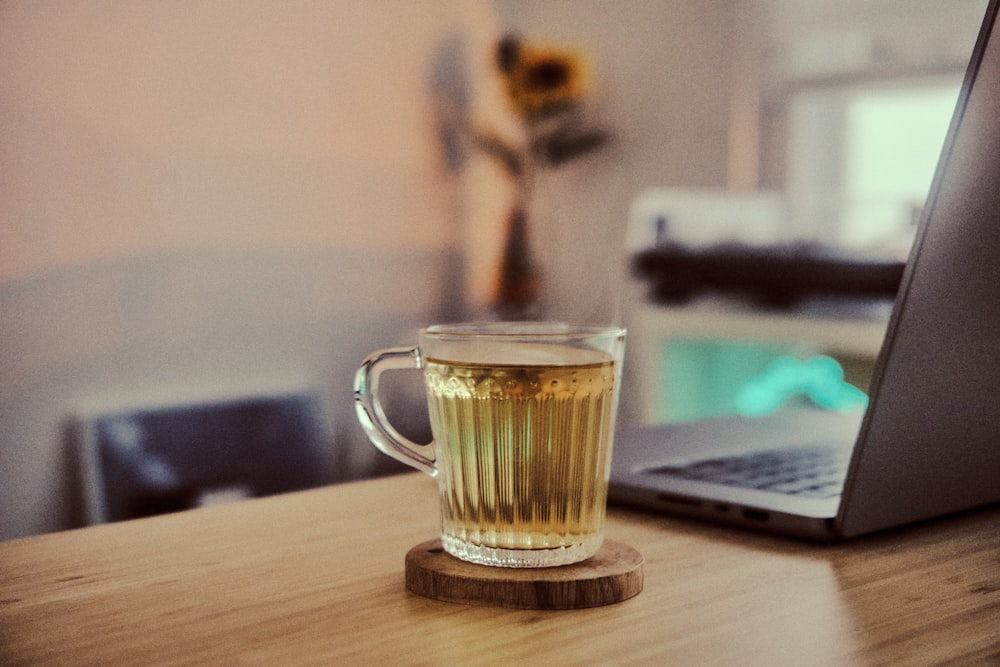 a cup of tea sitting on a table next to a laptop