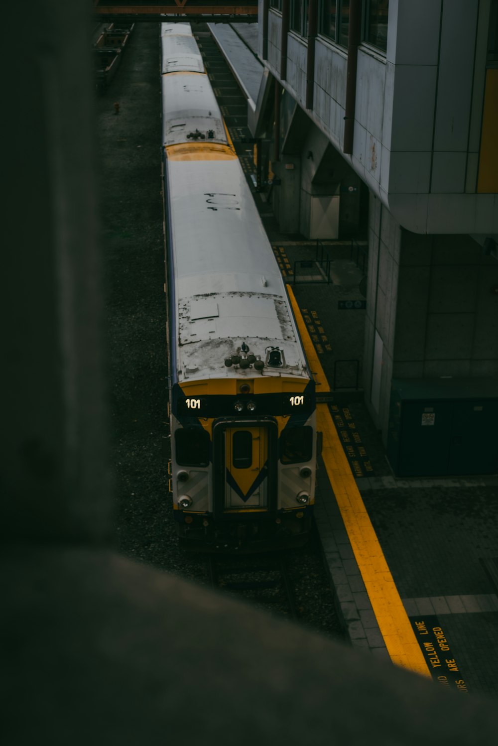 a yellow and white train parked at a train station
