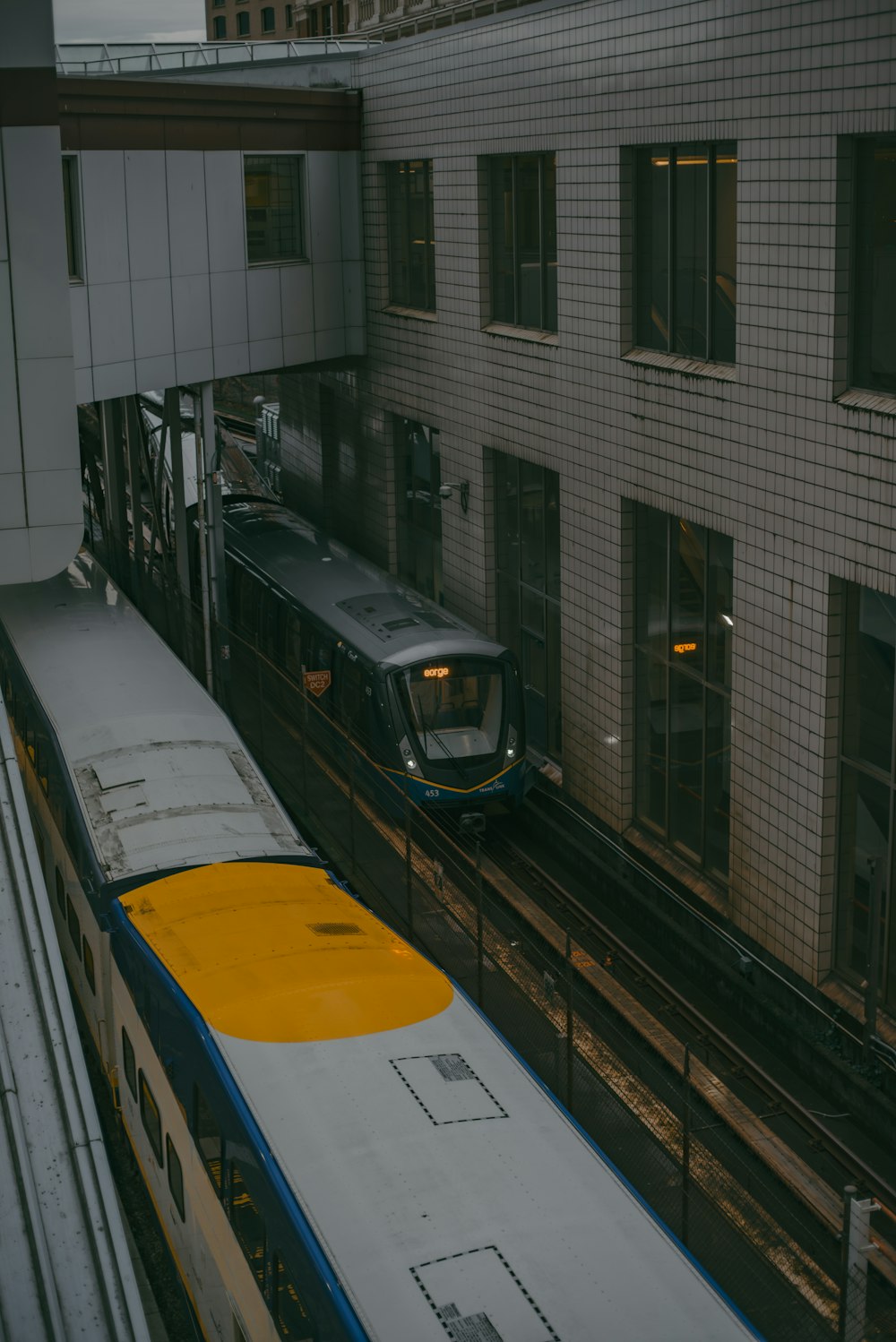 a train traveling down tracks next to a tall building