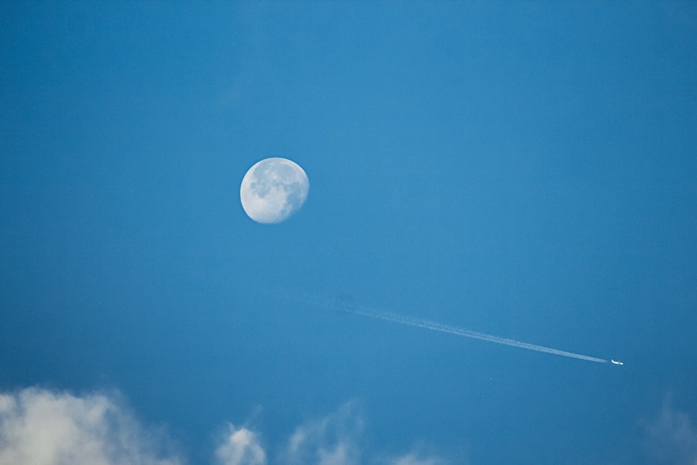 a plane flying in the sky with the moon in the background