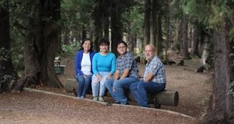 A group of people sitting quietly on logs, immersed in nature during a guided forest therapy session.