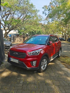 Blue SUV parked near a leafy tree with sunlight filtering through.