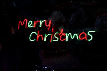 a merry christmas sign lit up in the dark