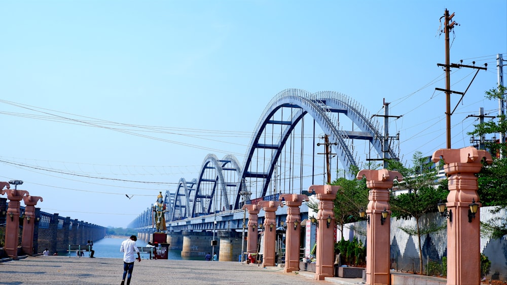 a man walking down a street next to a bridge