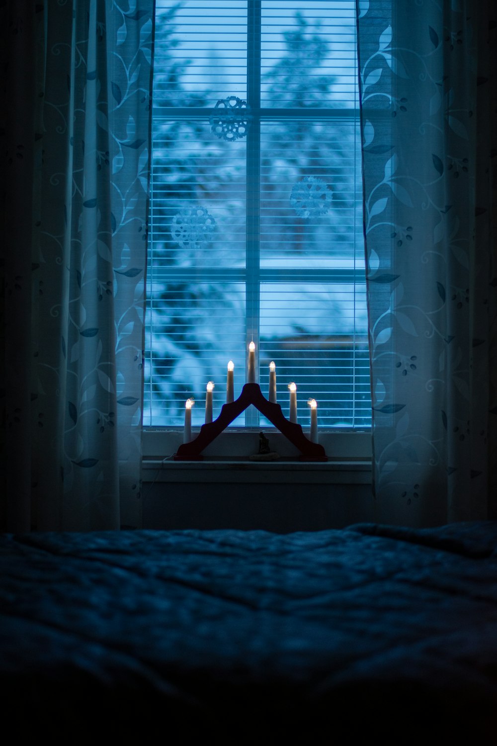 a room with a bed and a window with candles in it