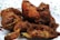 A close-up view of several pieces of deep-fried chicken arranged on a patterned plate. The chicken pieces are golden brown and crispy, with visible spices and crunchy texture on the surface. The plate shows a floral design around its edges.