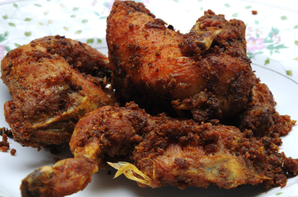 A close-up of golden, crispy fried chicken pieces steaming hot on a rustic wooden platter.