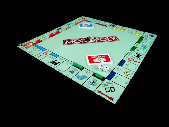 A Monopoly board game set up with properties, chance and community chest cards, dice, and game pieces arranged on the board. The board features iconic spaces like 'Go', 'Chance', and 'Free Parking', surrounded by property squares with various colors.