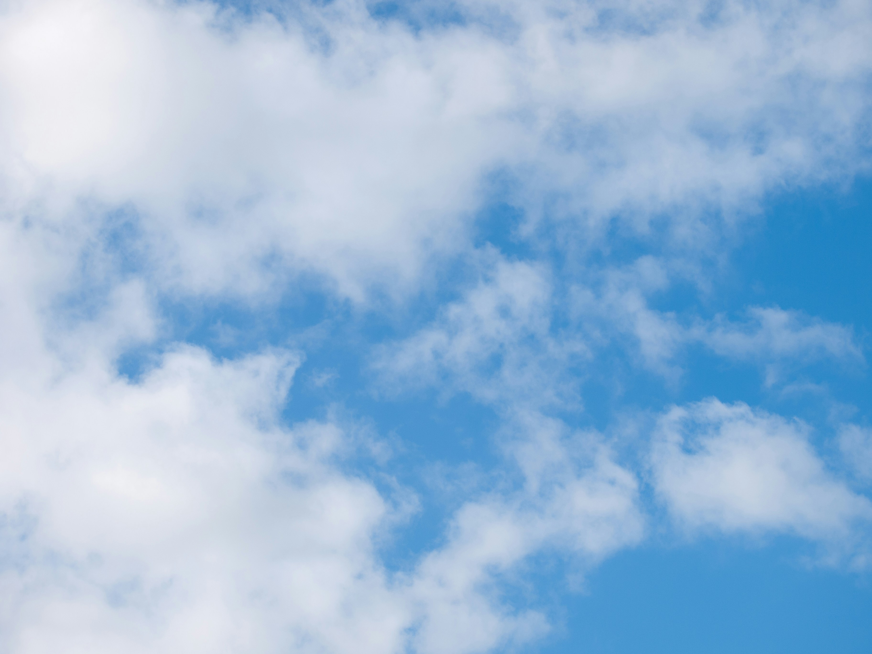 a plane flying through a cloudy blue sky