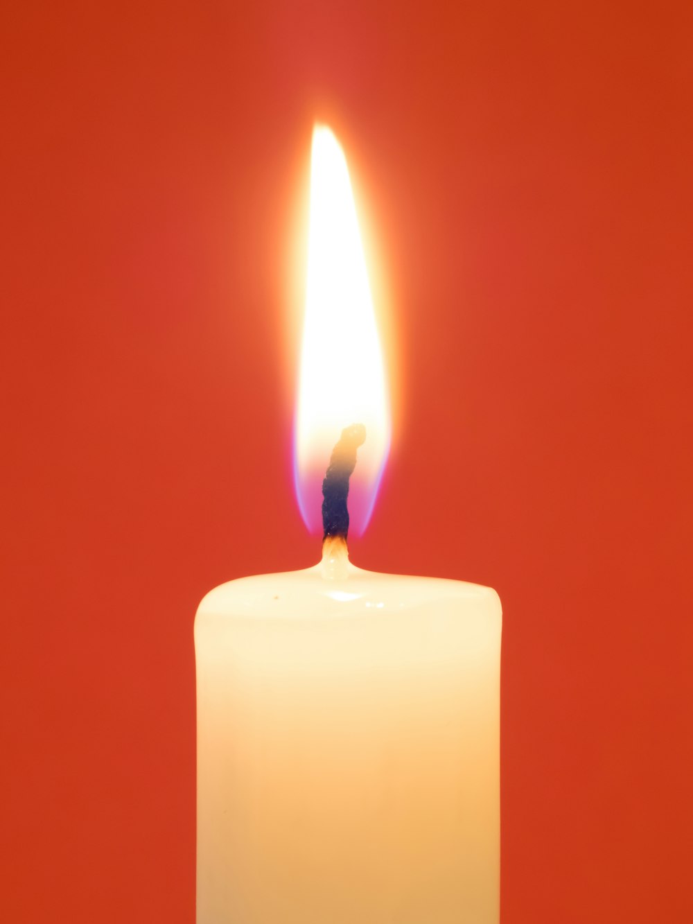 a lit candle with a red background