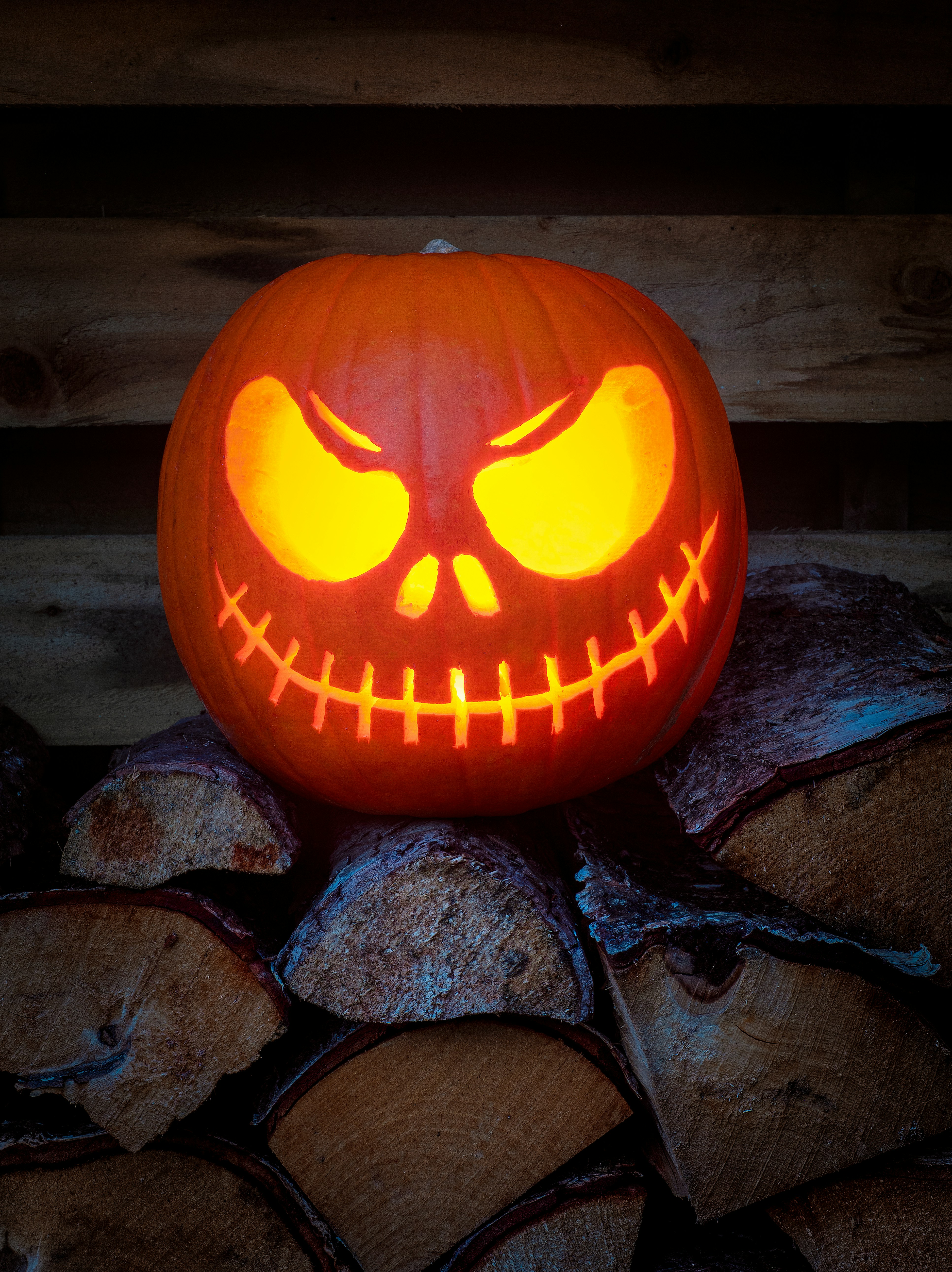 A carved jack o lantern sitting on top of a pile of logs photo – Free Face  Image on Unsplash, image size:3000x4008