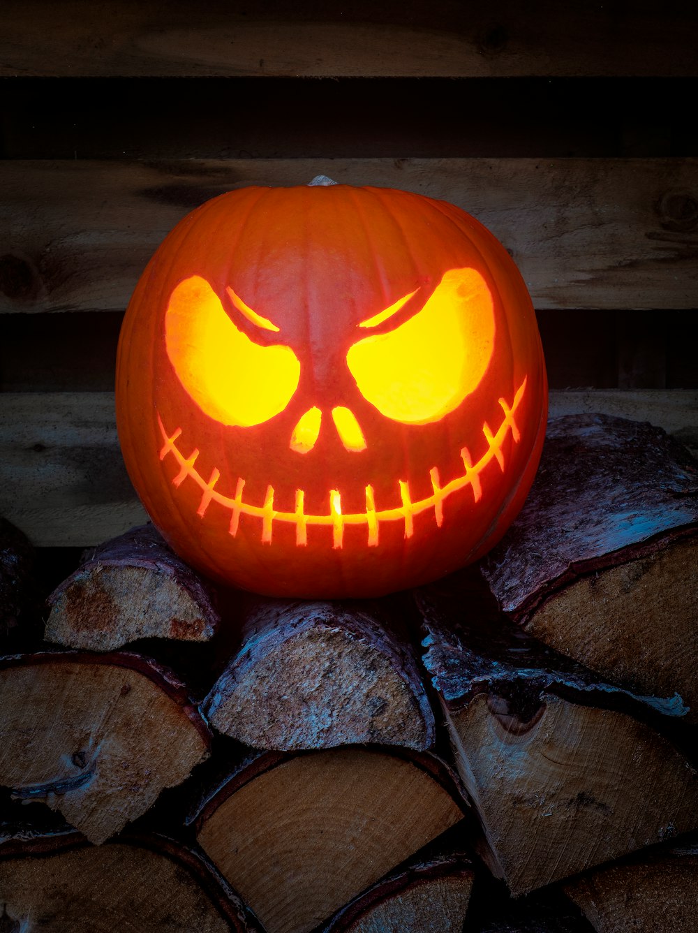 a carved jack o lantern sitting on top of a pile of logs