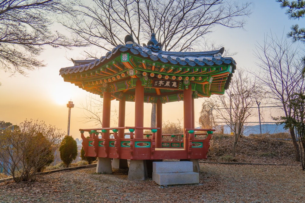 a red and green pavilion sitting in the middle of a park