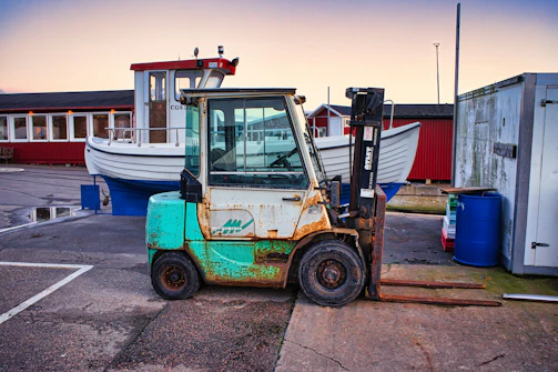 A gas-powered forklift unloading raw materials from a delivery truck at a busy dock.