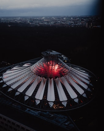 A sleek dome structure shielding a cityscape under a stormy sky with lightning in the distance.