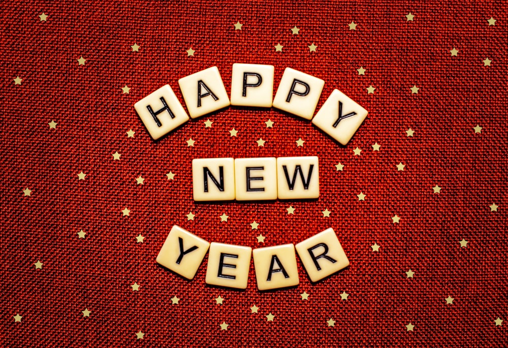 Feliz Año Nuevo deletreado con Scrabbles sobre un fondo rojo