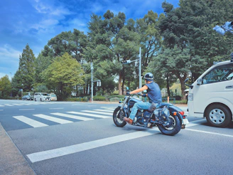 A bike taxi rider waiting patiently with a helmet in a calm green park setting.