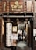 Entrance to a Japanese restaurant with wooden signage featuring Japanese characters. A large paper lantern with more Japanese writing is positioned outside the entrance. Several people are seen descending a staircase behind the entrance, with menus and posters advertising food and drink specials displayed prominently.