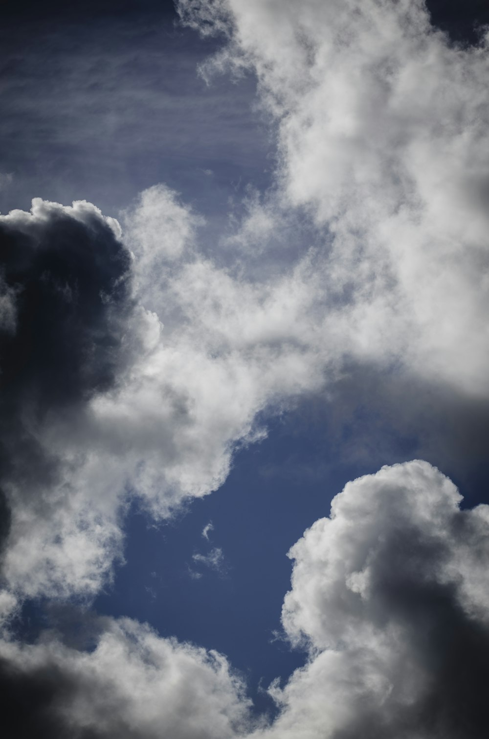 a plane flying through a cloudy blue sky