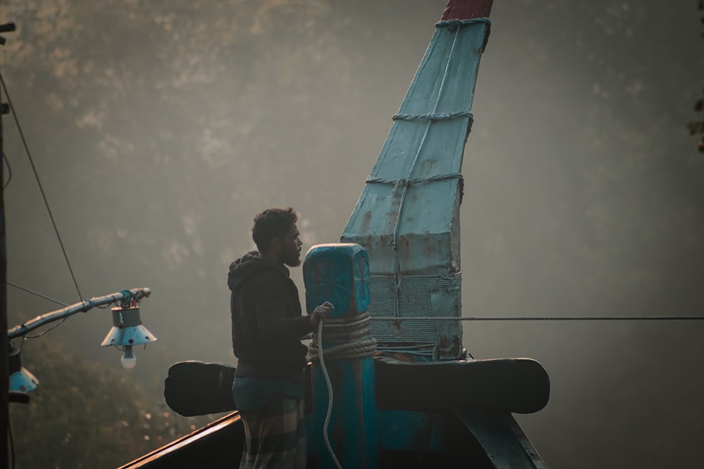 a man standing on top of a blue boat