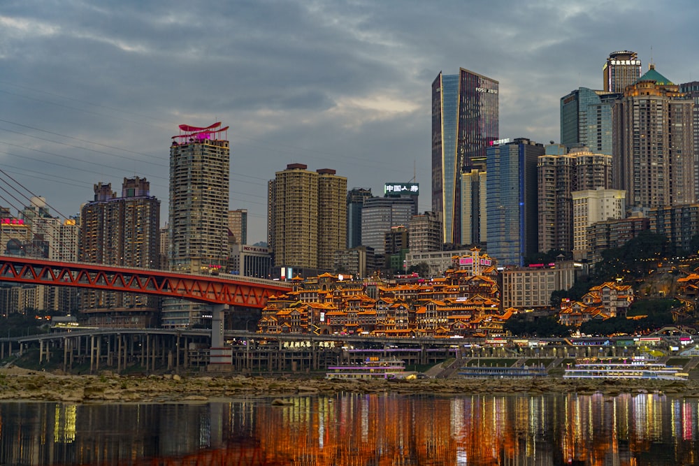 a red bridge over a body of water with a city in the background