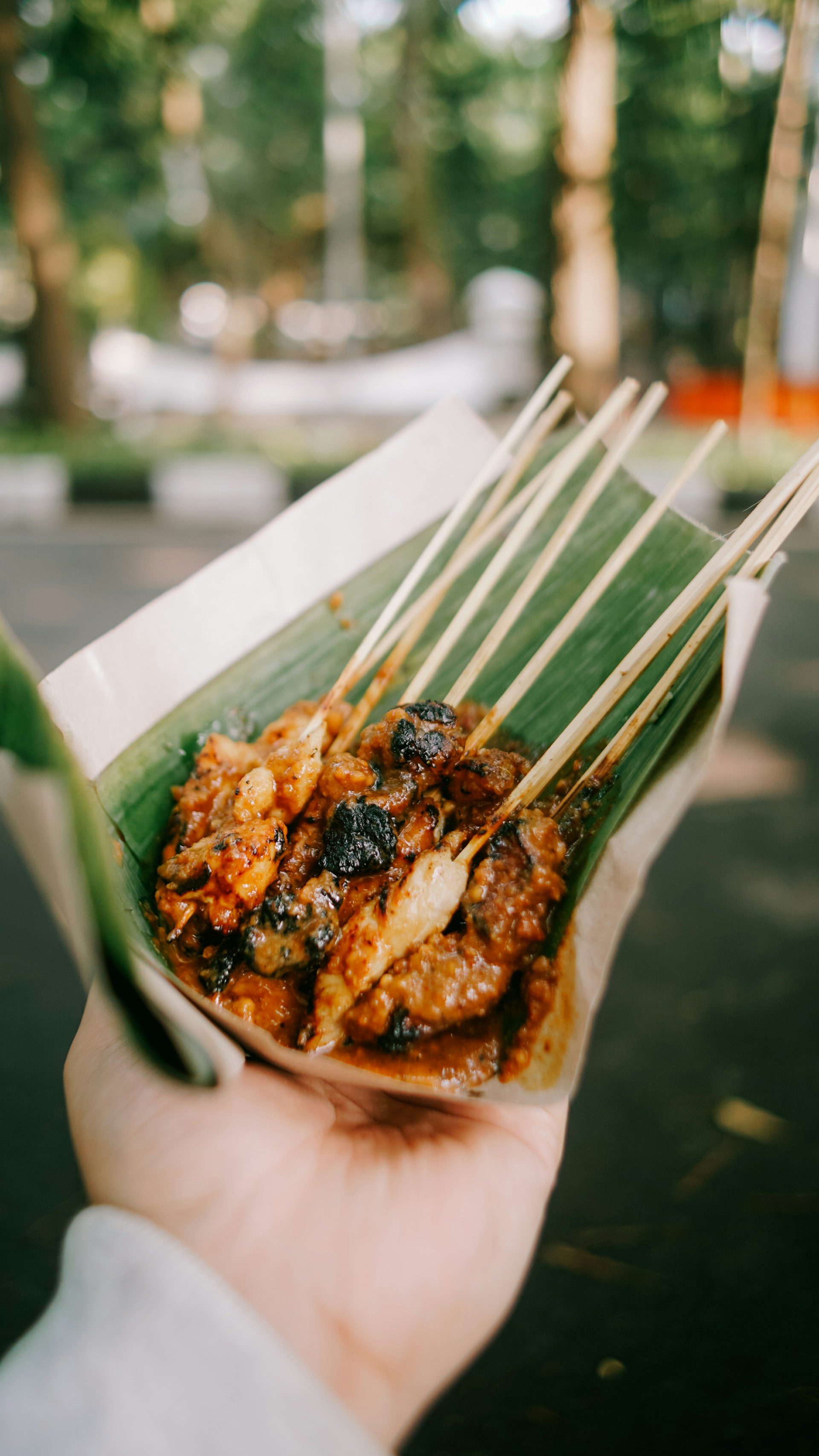 A close-up of sizzling grilled satay skewers with peanut sauce, highlighting the rich textures and colors.