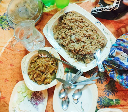 A warm, inviting table setting featuring a colorful spread of Somali dishes including rice, sambusas, and fresh salad.