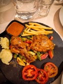 A colorful plate featuring grilled chicken with fresh vegetables and dipping sauce.