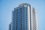 A modern high-rise building with a rectangular shape, featuring numerous windows and a glass facade. The building has a sleek, contemporary design, with metallic elements and a series of uniformly arranged lines adding to its architectural elegance.