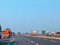 Wide shot of a highway with mc logistica trucks traveling under a clear sky.