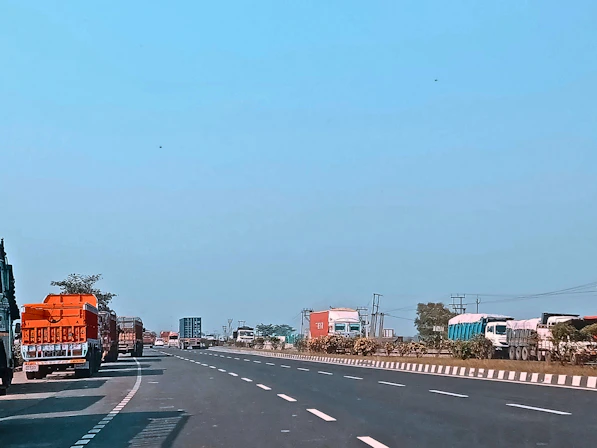 A modern fleet of heavy-duty trucks lined up on an open highway under a clear sky, ready for cargo transport.