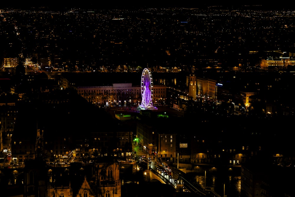 a city at night with a ferris wheel lit up