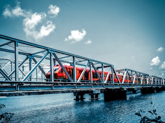 a red train traveling across a bridge over water