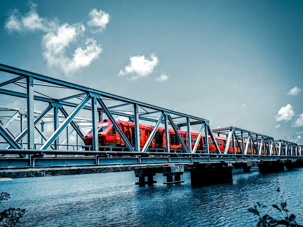 a red train traveling across a bridge over water
