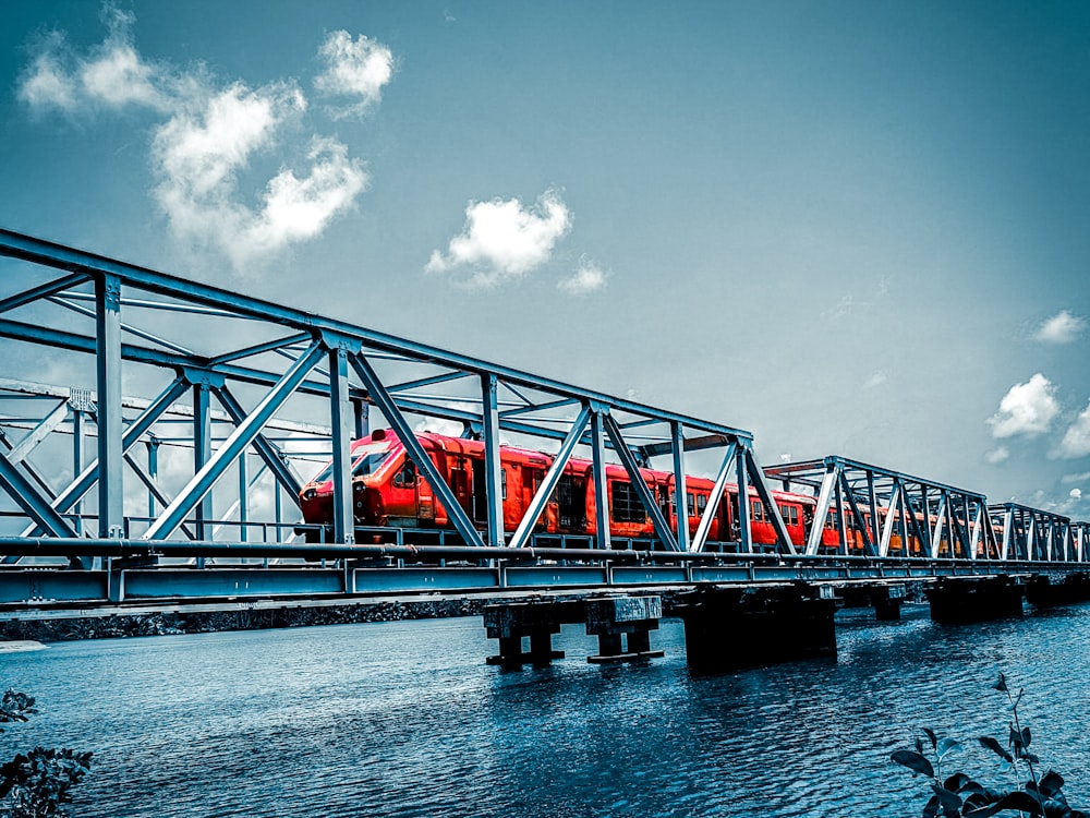 a red train traveling across a bridge over water