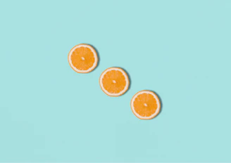 three slices of orange sitting on top of a blue surface