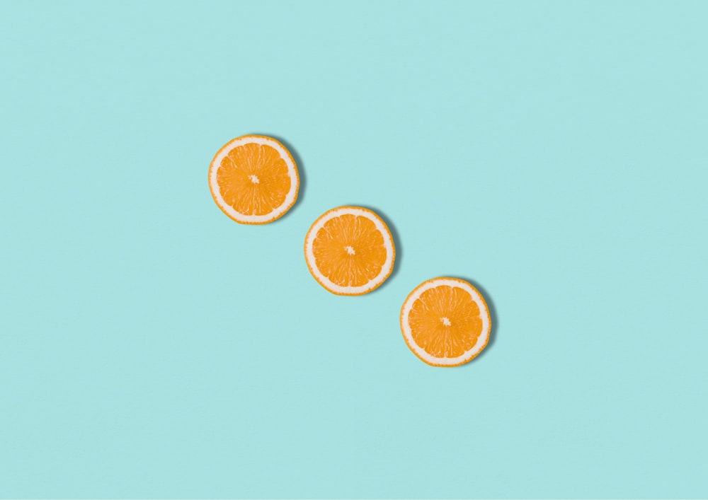 three slices of orange sitting on top of a blue surface