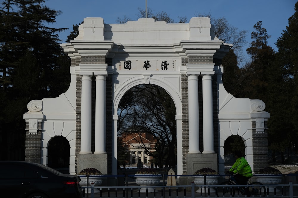 a person riding a bike in front of a white arch