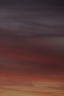 A horizon filled with gradient colors transitioning from deep orange and red to darker shades of blue and grey, resembling a sunset or sunrise.