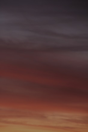 A horizon filled with gradient colors transitioning from deep orange and red to darker shades of blue and grey, resembling a sunset or sunrise.