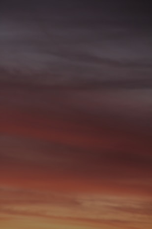A horizon filled with gradient colors transitioning from deep orange and red to darker shades of blue and grey, resembling a sunset or sunrise.