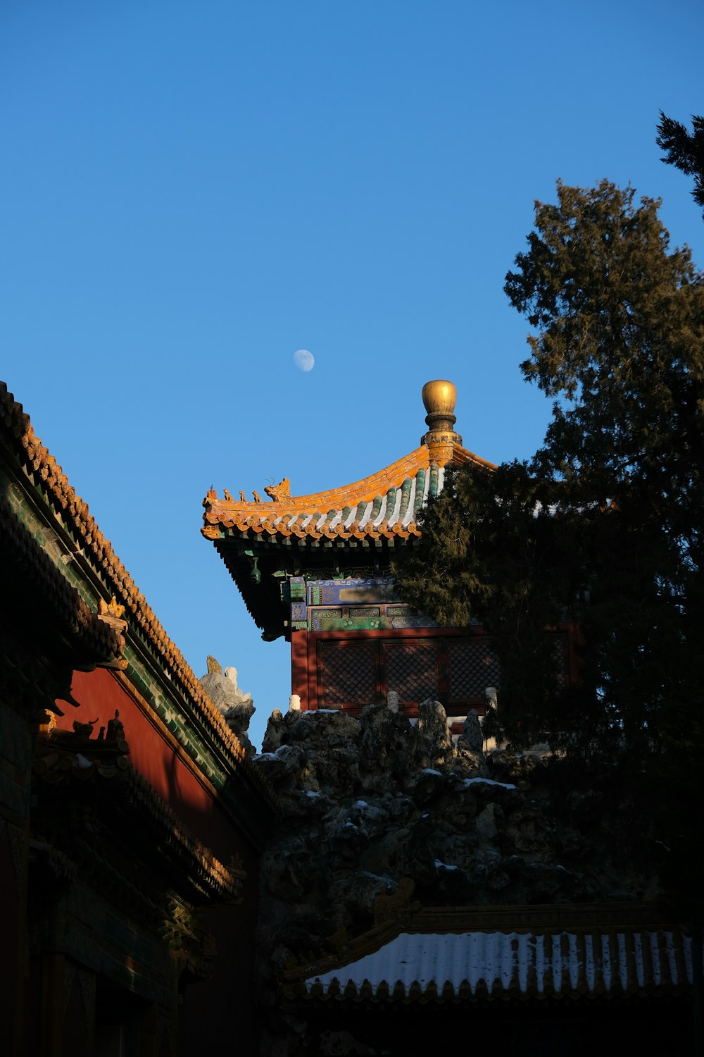 a view of the roof of a building with a half moon in the sky