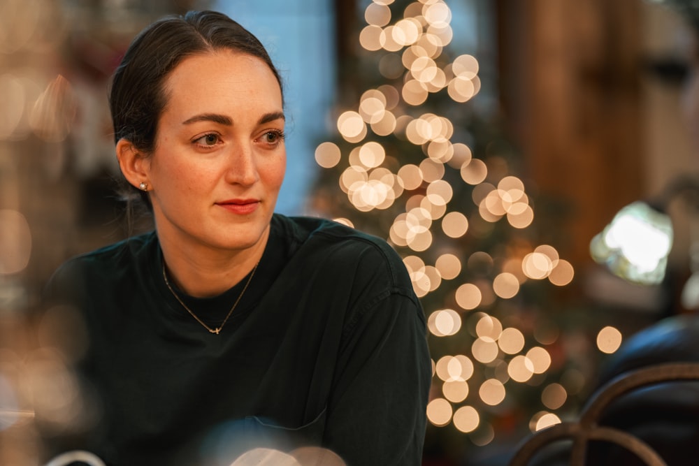 a woman sitting at a table in front of a christmas tree