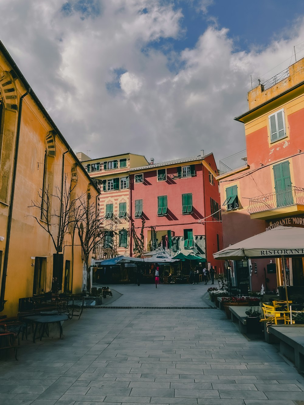 a street lined with buildings and tables under a cloudy sky