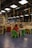 A library or reading area with colorful seating arrangements is filled with children and adults. The ceiling features hanging decorative spirals in various colors. Bookshelves and tables are scattered around, with people engaging in reading or activities.