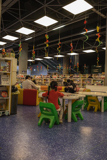 A vibrant scene of children eagerly reading books inside a colorful mobile library van in a serene village setting.