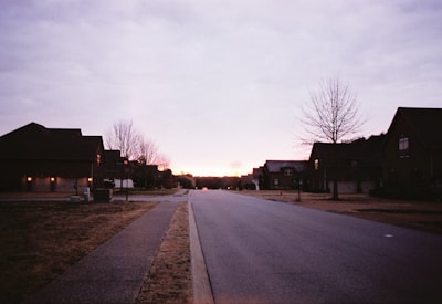 Evening view of a quiet rural street lined with trees and small homes.