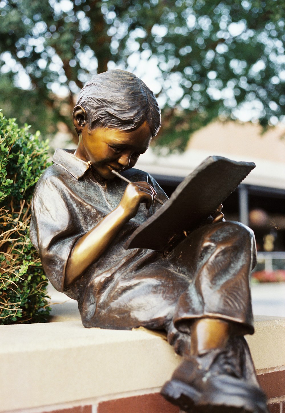 a bronze statue of a boy reading a book